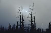 Sun peeking around mountain through mist near Haines 
