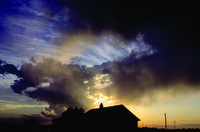 House silhouetted in front of storm clouds