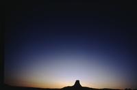 Silhouette of Devil's Tower against sunset sky