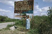 Woman standing beneath Genesis sign on highway