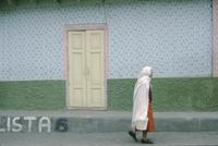 An old woman walking alone, carrying a bucket