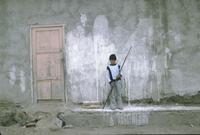 Boy with a long stick in front of a building